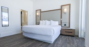 Una habitación de hotel moderna con una cama grande, mesitas de noche e iluminación en la pared.
