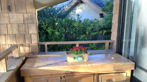 Un banc en bois avec un pot de fleurs et un panier en osier placé en dessous.