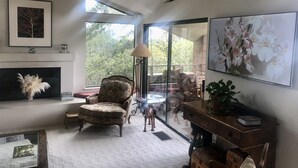 Un salon spacieux doté d’une cheminée, d’une grande fenêtre et offrant une vue sur l’extérieur.