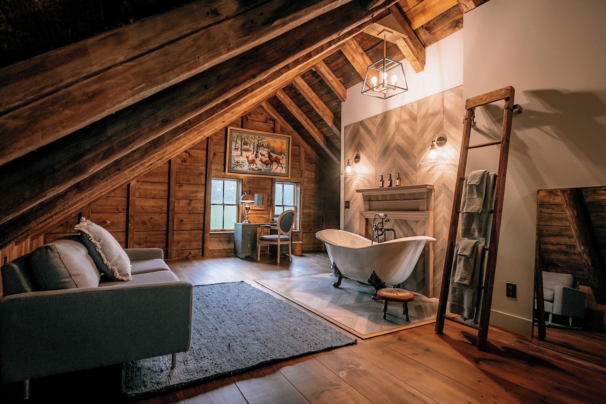 Ein gemütliches Schlafzimmer im Dachgeschoss mit schrägen Wänden, einer alten Badewanne, einer Holzleiter und einem rustikalen Kamin.