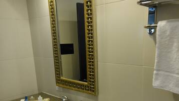 A bathroom with a granite countertop, a white sink, a gold-framed mirror, and a towel rack with a white towel.