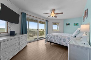 A bedroom with a bed, a dresser, a ceiling fan, a TV, and a view of the outdoors. - 8BR Oceanfront home - Game & theater rooms, private pool, hot tub ★★★★★ (Waves)