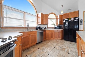A kitchen with wooden cabinets, a stainless steel dishwasher, a black refrigerator, and a microwave.