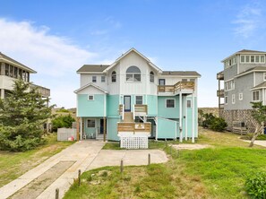 A two-story house with a front porch, a small staircase, and a fenced yard. - 8BR Oceanfront home - Game & theater rooms, private pool, hot tub ★★★★★ (Waves)