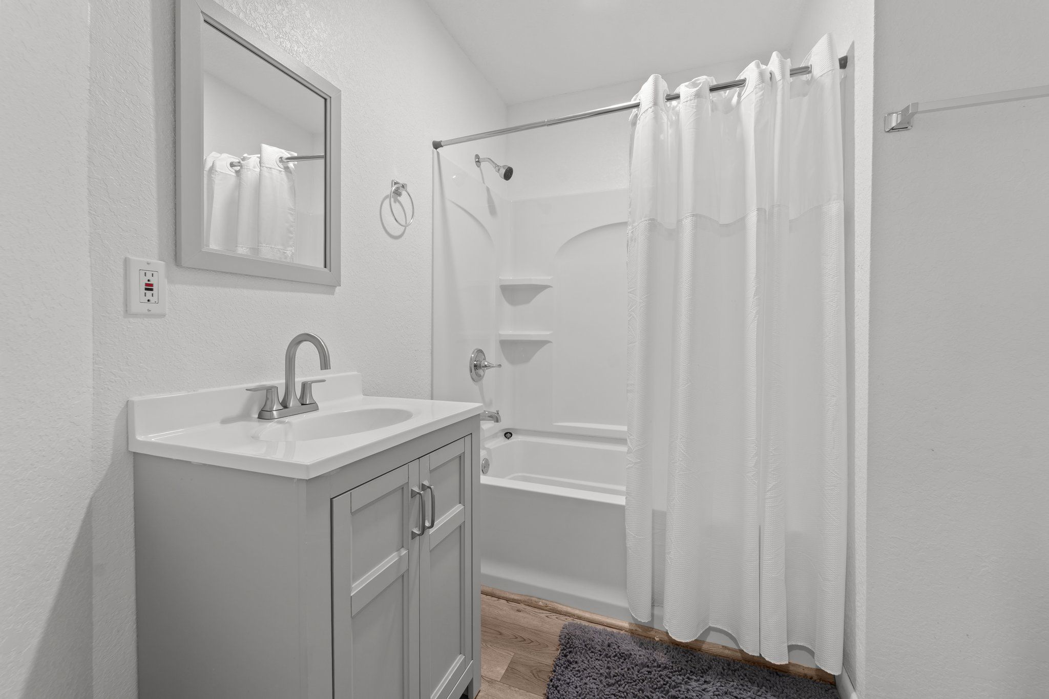Une salle de bain avec un lavabo blanc, un miroir et une baignoire.