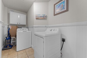 A laundry area with a washing machine, dryer, and vacuum cleaner. - 8BR Oceanfront home - Game & theater rooms, private pool, hot tub ★★★★★ (Waves)
