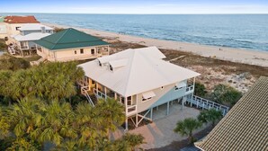 Une propriété située en bord de mer, comprenant plusieurs bâtiments, dont une maison principale dotée d’un toit végétalisé et une construction plus petite avec un toit rouge.