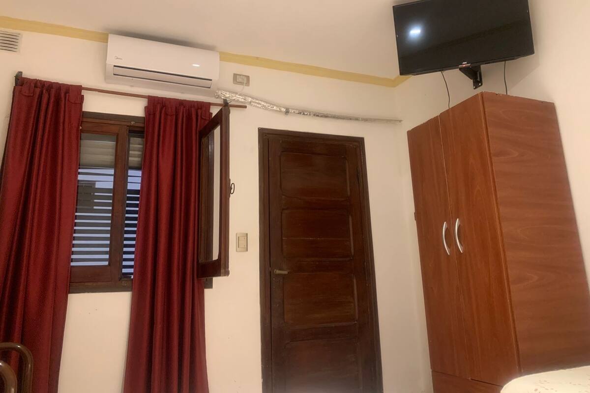 Quarto com guarda-roupa de madeira, porta fechada e ar condicionado fixado na parede.