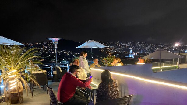 Un bar situé sur le toit, avec une terrasse, une vue sur la ville et un éclairage décoratif.