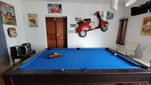 A pool table with a red scooter, a vintage motorcycle sign, and a 'Beer' sign. - Casa Francisco Hotel (Quito)