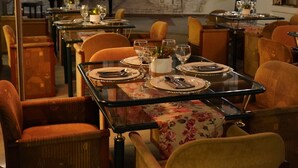 Un espace repas avec des tables dressées pour le repas, des chaises et un piano en arrière-plan.