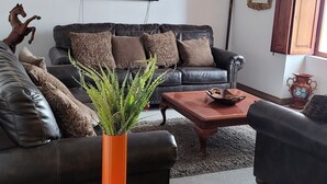 A living room with a leather sofa, a coffee table, and a TV mounted on the wall. - Casa Francisco Hotel (Quito)