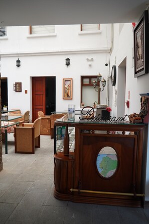 A cozy interior with a wooden bar counter, wicker furniture, and a map. - Casa Francisco Hotel (Quito)