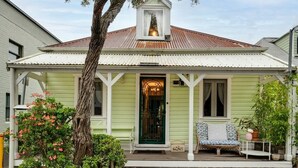 A green house with a white porch, a bench, and a tree in front. - The Chelsea Cottage, Alfresco Living East Redfern (Redfern)
