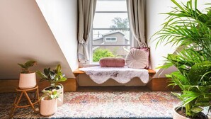 A cozy room with a window seat, a patterned rug, and potted plants. - The Chelsea Cottage, Alfresco Living East Redfern (Redfern)