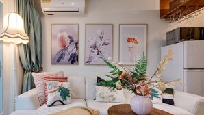 A modern living room with a white sofa, a wooden coffee table, and three framed floral artworks on the wall. - The Chelsea Cottage, Alfresco Living East Redfern (Redfern)