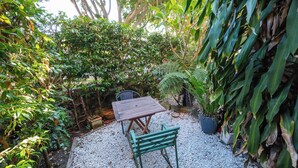 A patio area with a table and chair, surrounded by dense foliage and a variety of plants. - Bondi local garden living, 5 mins walk to beach (Bondi Beach)
