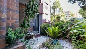 A courtyard with a patio table, potted plants, and a brick wall. - Bondi local garden living, 5 mins walk to beach (Bondi Beach)