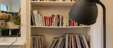 A bookshelf with books and vinyl records, a black desk lamp, and a white cabinet with doors.