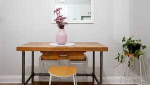 A dining table with a pink vase and flowers, a chair, and a potted plant. - Incredible Beachside Location 4 Bed Apartment (Bondi Beach)