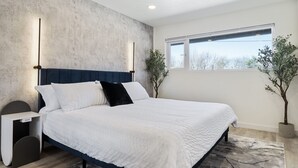 Een moderne slaapkamer met een groot bed, nachtkastjes en een raam met uitzicht.