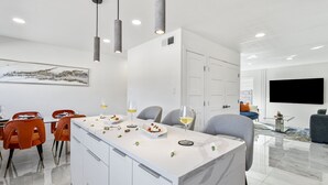 Een moderne keuken met een centraal eiland, witte kastjes en hanglampen.