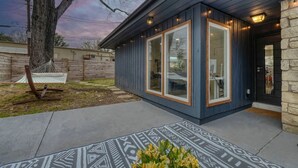 Een modern huis met een donkere gevel, grote ramen en een stenen muur.