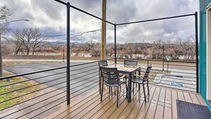 A wooden deck with a table and chairs, overlooking a parking area and distant landscape. - Grand Junction Home ~ 1 Mi to Downtown (Grand Junction)