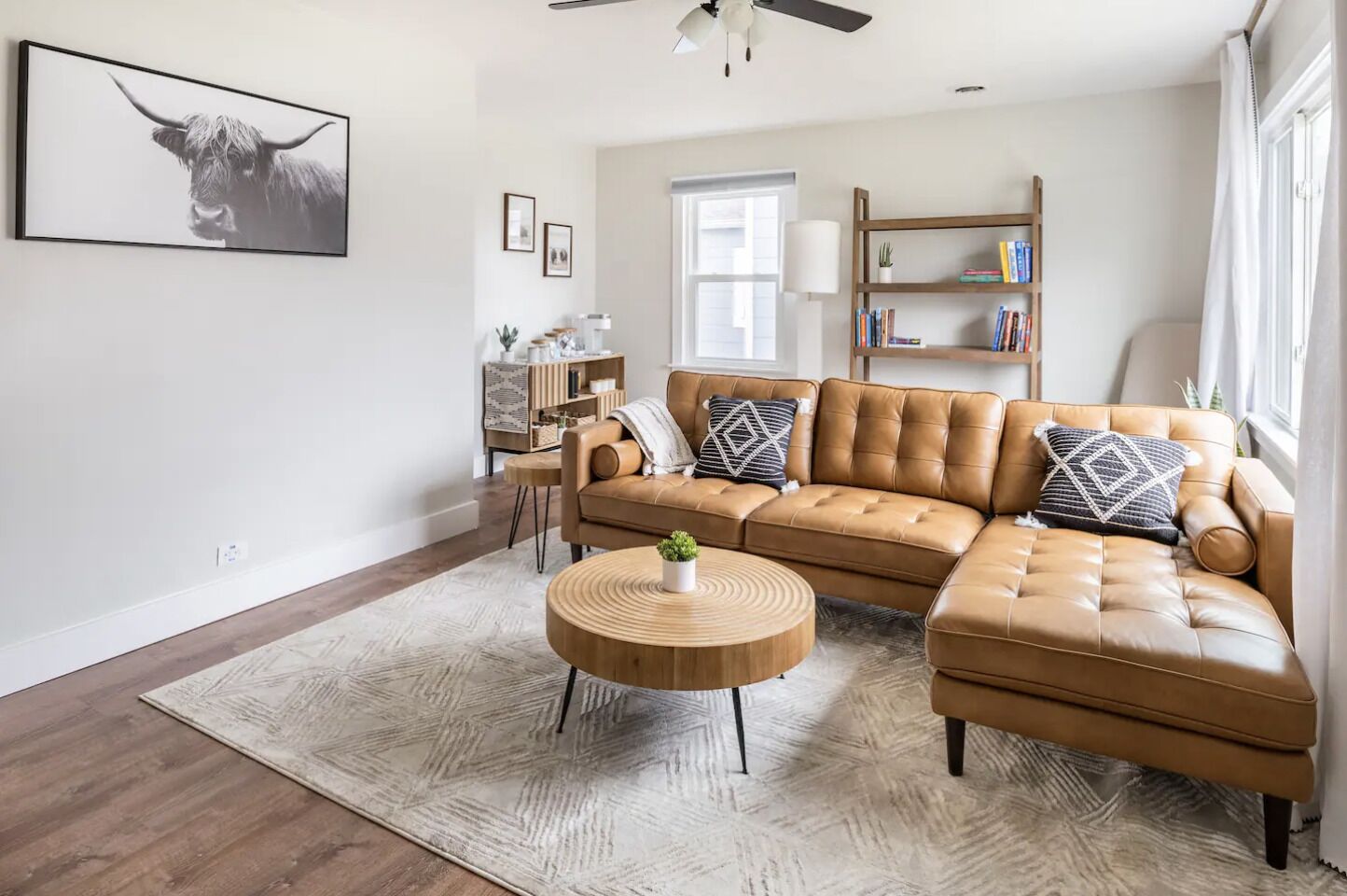 A modern living room with a leather sofa, a round coffee table, and a large framed picture on the wall.