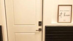 A white door with a small window, a wall-mounted vent, and a framed sign above the vent that reads "MAKE YOURSELF at home".