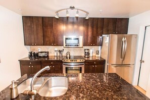Eine moderne Küche mit dunklen Holzschränken, Edelstahlgeräten, Granitwerkplatten und einem eingebauten Backofen.