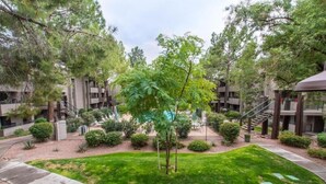 A courtyard with a central lawn, surrounded by trees and a building with multiple balconies. - Top Floor Condo Minutes from Old Town (Scottsdale)