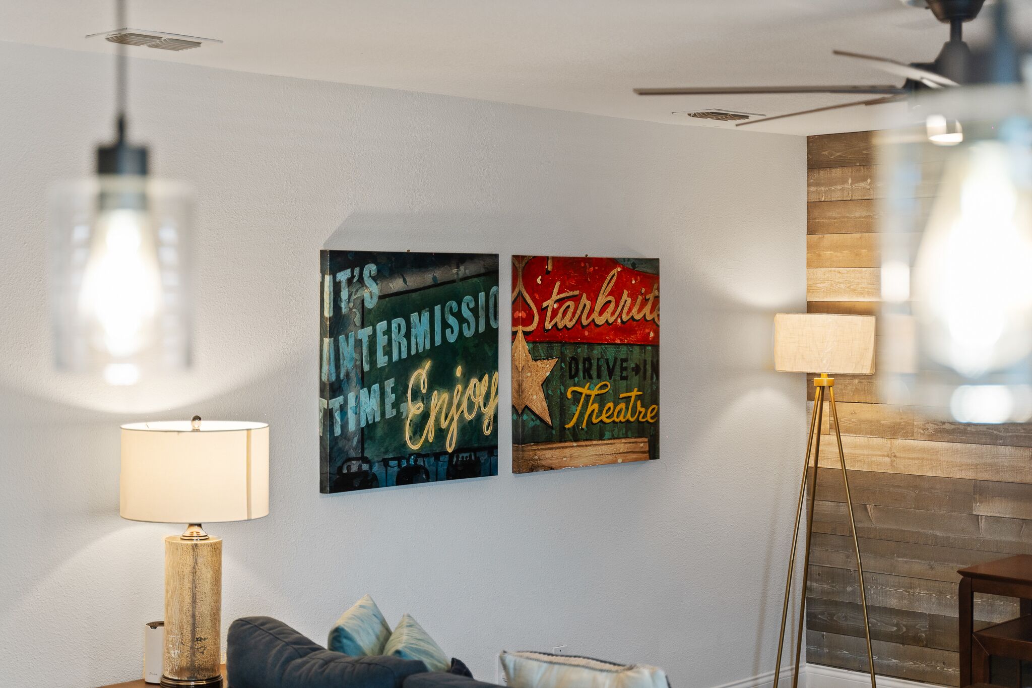 Una habitación con una lámpara moderna, un sofá y dos obras de arte en la pared.