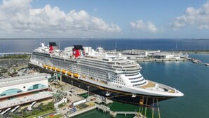 Un grand navire de croisière a accosté dans un port doté de plusieurs ponts et d’un bâtiment terminal situé à proximité.