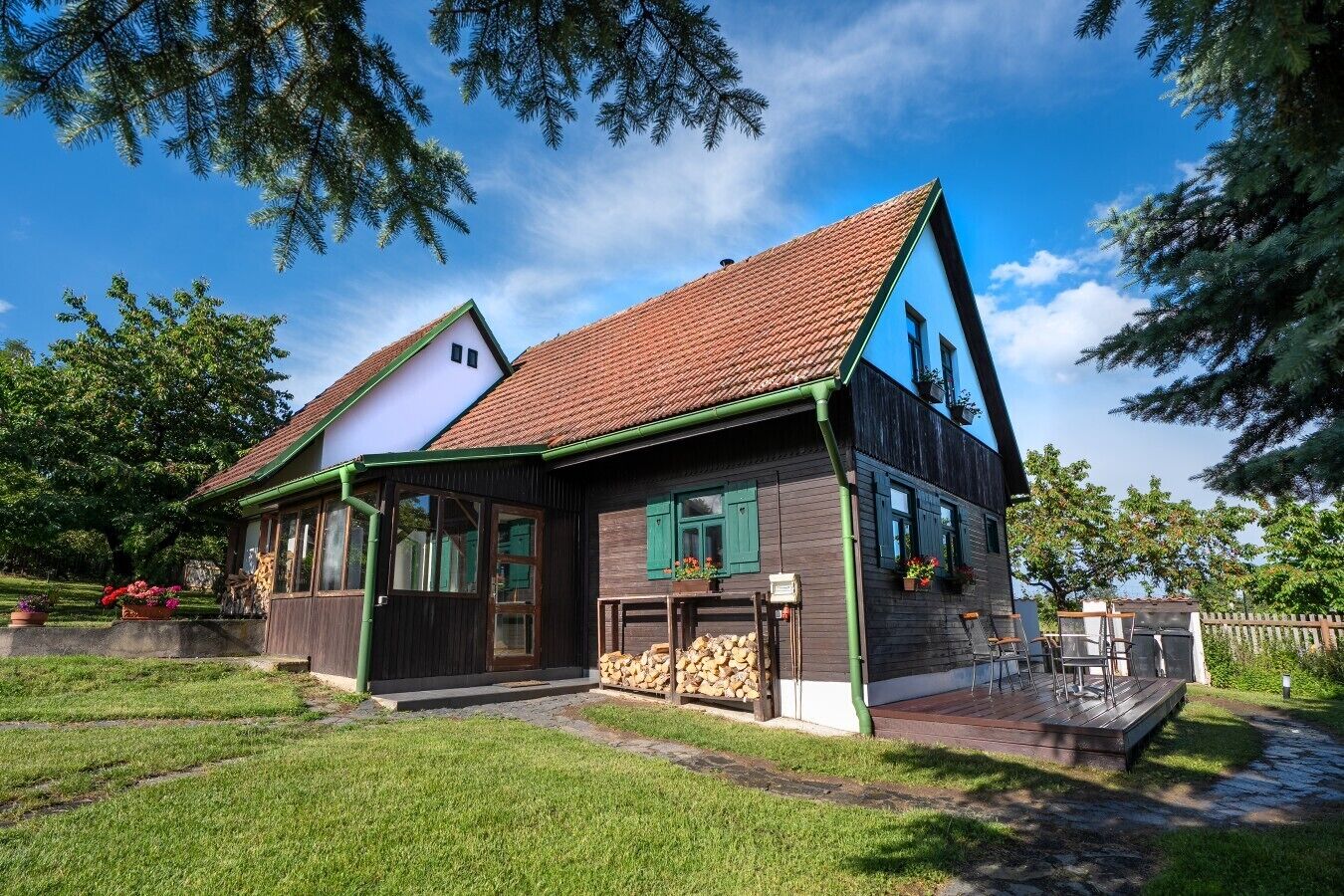 A two-story house with a sloped roof, a front porch, and a small deck area.
