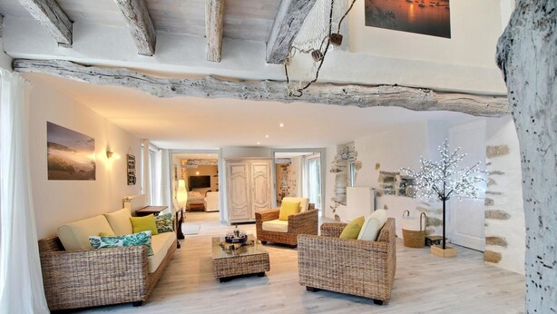 A spacious living area with wicker furniture, a coffee table, and a decorative tree. There is a view into another room with a bed and a wardrobe. - Heol - AMBON - Gîte (AMBON)