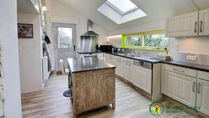 A modern kitchen with a skylight, wooden island, and white cabinets. - Heol - AMBON - Gîte (AMBON)