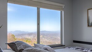 A bedroom with a large window offering a mountain view. - Incredible Mtn. Views, Indoor & Out Door Pools, Cozy Loft, Minutes to Downtown! (Gatlinburg)