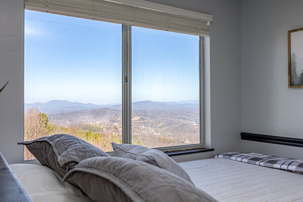 A bedroom with a large window offering a mountain view. - Incredible Mtn. Views, Indoor & Out Door Pools, Cozy Loft, Minutes to Downtown! (Gatlinburg)