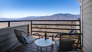 A balcony with a table and two chairs, overlooking a mountainous landscape. - Incredible Mtn. Views, Indoor & Out Door Pools, Cozy Loft, Minutes to Downtown! (Gatlinburg)