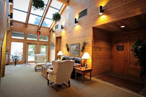 A cozy lobby with wooden walls, a leather sofa, and two lamps.