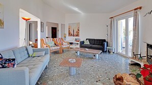 A spacious living room with a grey sofa, a wooden chair, a coffee table, and a fireplace.