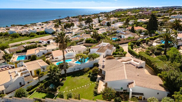 A coastal residential area with houses, a swimming pool, and a view of the sea.