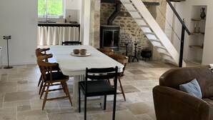 Un comedor amplio con una mesa larga y sillas, una chimenea de piedra y una escalera que sube a un nivel superior.