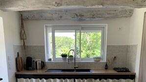 Una cocina con ventana, pileta, estufa y encimera.