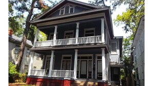 A two-story house with a porch and a front door. - In Through The Side Door (Victorian District) (Savannah)