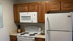 Une cuisine avec des meubles de rangement en bois, un fourneau blanc, un four à micro-ondes et un réfrigérateur.