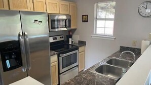 A kitchen with a stainless steel refrigerator, microwave, oven, and sink. - Equilibrium (Islands Bungalow) (Savannah)