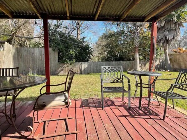 Enjoy dining or socializing in this covered patio area with a deck, chairs, and tables.