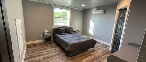 Une chambre à coucher avec un lit, une table de chevet, une fenêtre et une porte.